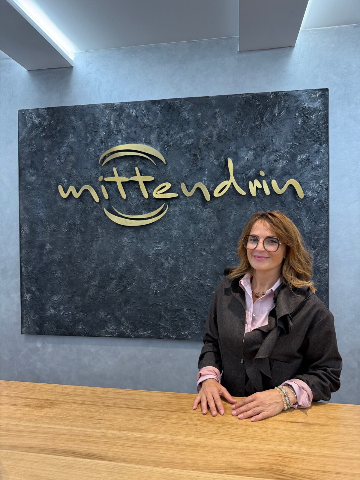 Die Inhaberin am Tresen der Boutique vor dem goldenen mittendrin Schriftzug
